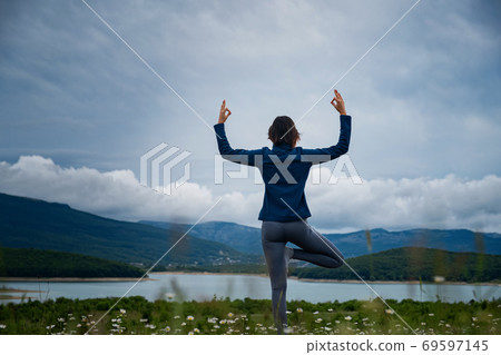 A young woman doing yoga in the field. 69597145