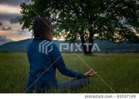 A young woman doing yoga in the field. 69597149