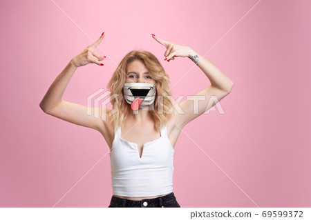 Portrait of young girl with emotion on her protective face mask isolated on studio background. Beautiful female model, funny expression Portrait of young girl with emotion on her protective face mask isolated on studio background. Beautiful female model, funny expression 69599372