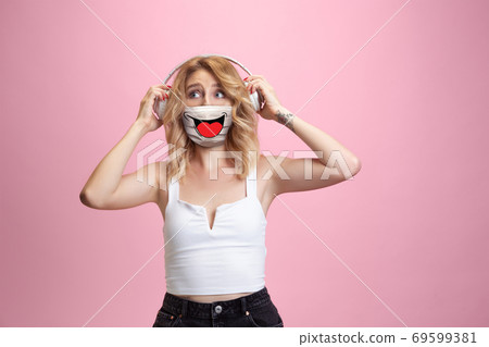 Portrait of young girl with emotion on her protective face mask isolated on studio background. Beautiful female model, funny expression 69599381