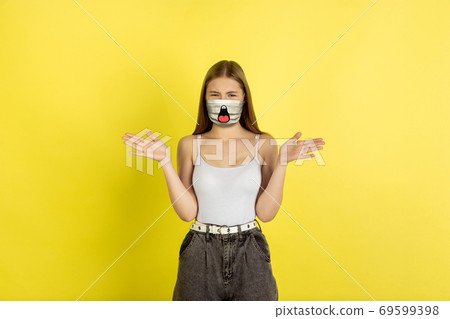 Portrait of young girl with emotion on her protective face mask isolated on studio background. Beautiful female model, funny expression 69599398