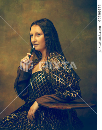 Young woman as Mona Lisa on dark background. Retro style, comparison of eras concept. Young woman as Mona Lisa on dark background. Retro style, comparison of eras concept. 69599473