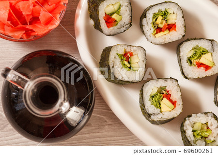 Sushi rolls with rice, vegetable and seafood on plate with bottle of soy sauce Sushi rolls with rice, vegetable and seafood on plate with bottle of soy sauce 69600261