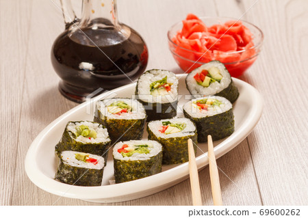 Sushi rolls with rice, vegetable and seafood on plate with bottle of soy sauce 69600262