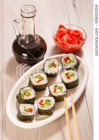 Sushi rolls with rice, vegetable and seafood on plate with bottle of soy sauce 69600264