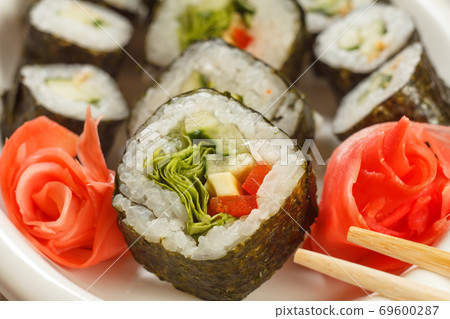 Hosomaki with vegetables. Sushi roll with nori, rice, avocado and bell pepper Hosomaki with vegetables. Sushi roll with nori, rice, avocado and bell pepper 69600287