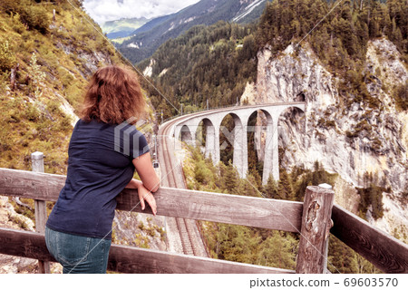 Female tourist looks at Landwasser Viaduct in Switzerland 69603570
