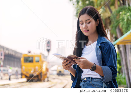 Traveler young woman looking passport with ticket in her hand 69605378