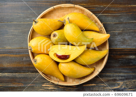 Eggfruit or canistel in a bamboo tray on wooden table, Thai fruit 69609671