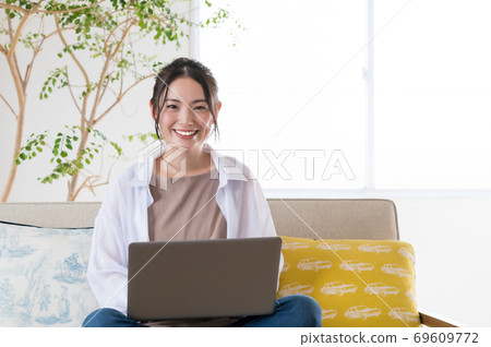 年輕女子坐在沙發上和遠程辦公 69609772