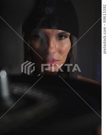Brunette smoking hookah in dark room 69613392