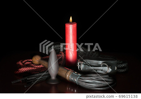 red wax candle with fire and leather whip with rope for tying 69615138