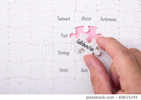 Hand holding piece of jigsaw puzzle with Collaboration wording Hand holding piece of jigsaw puzzle with Collaboration wording 69615245