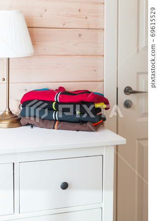 Colorful fleece jackets laying on a white chest of drawers 69615529