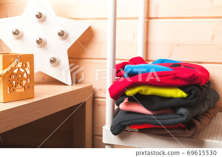 Stack of colorful fleece jackets lays in a wooden room Stack of colorful fleece jackets lays in a wooden room 69615530