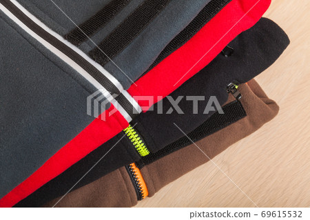 Colorful fleece jackets lay stacked on a wooden desk 69615532