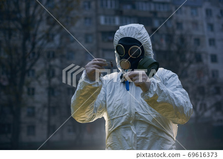 Scientist doing research outdoors, wearing white coverall and gas mask Scientist doing research outdoors, wearing white coverall and gas mask 69616373