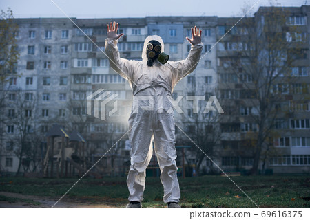 Scientist doing research outdoors, wearing white coverall and gas mask 69616375