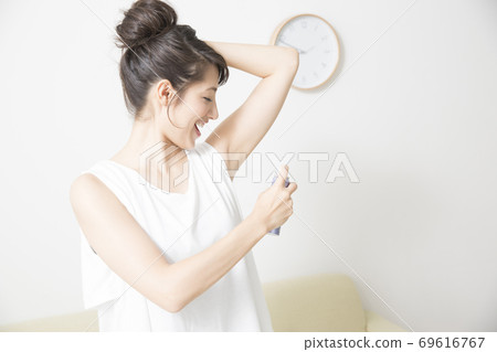 一個女人用除臭劑噴霧 一個女人用除臭劑噴霧 69616767