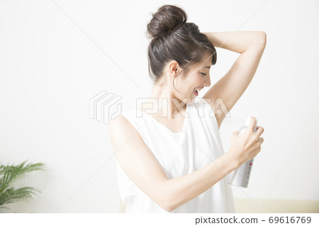A woman with a deodorant spray A woman with a deodorant spray 69616769