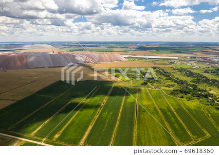 Mountains of products for the production of potash salt and a green field.Salt mountains near the city of Soligorsk.Production of fertilizers for the Land. Belarus. 69618360