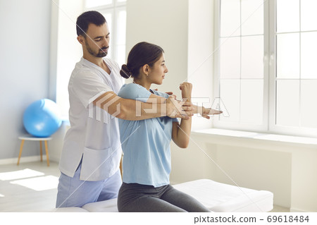 Physiotherapist and patient working on arm injury, doing medical exercise, stretching muscles 69618484