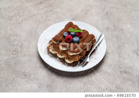 portion of Classic tiramisu dessert with raspberries and blueberries on grey concrete background portion of Classic tiramisu dessert with raspberries and blueberries on grey concrete background 69618570