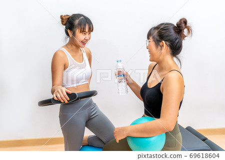 Two young Asian women taking a water break during their fitness exercise Two young Asian women taking a water break during their fitness exercise 69618604