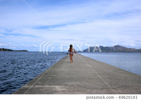 A girl running towards the sea 69620181