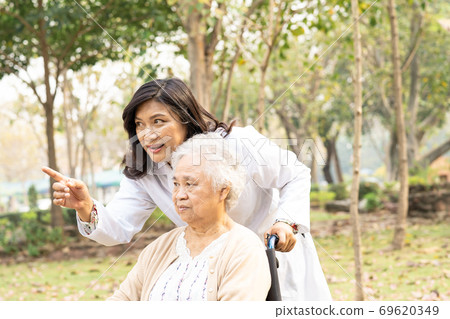 Doctor help and care Asian senior woman patient sitting on wheelchair at hospital. 69620349