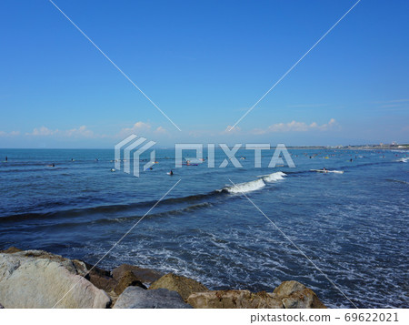People surfing on sea waves under blue sky. Katase Nishihama beach is one of Japan's most popular beaches 69622021
