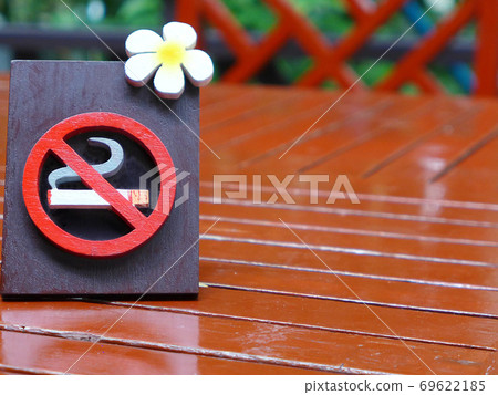 The sign "No smoking" is made of stucco on a red wooden table in a restaurant. The sign "No smoking" is made of stucco on a red wooden table in a restaurant. 69622185