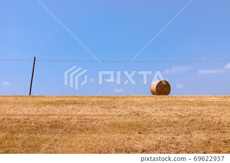 Hay roll on a freshly cut field against a blue sky. Minimalistic photo Hay roll on a freshly cut field against a blue sky. Minimalistic photo 69622937