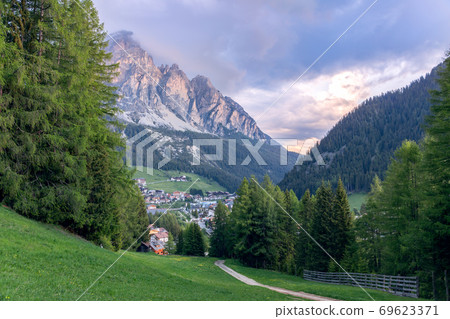 A path leading through an alpine meadow to the village of Corvara A path leading through an alpine meadow to the village of Corvara 69623371