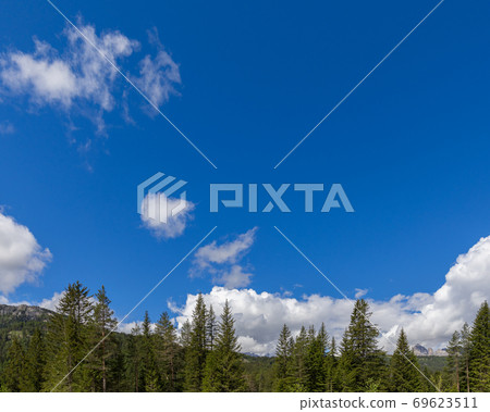 Beautiful blue sky with textured clouds and mountain peaks along the bottom of the image 69623511
