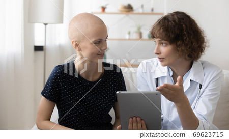Doctor and sick female cancer patient discuss results on pad 69623715