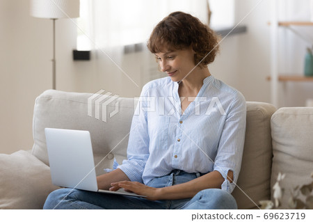 Young Caucasian woman look at laptop screen working Young Caucasian woman look at laptop screen working 69623719
