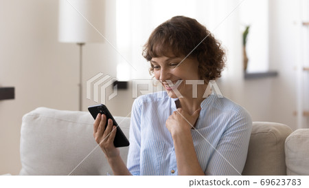 Happy Caucasian woman smile reading message on smartphone Happy Caucasian woman smile reading message on smartphone 69623783