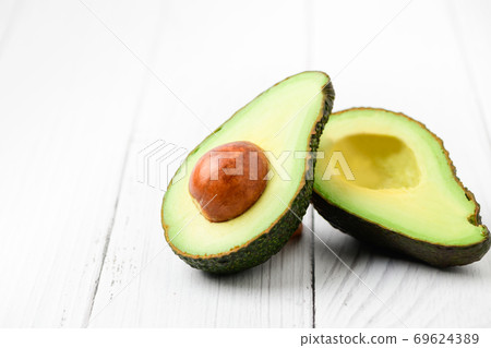 Avocado half isolated on white wood background. Avocado half isolated on white wood background. 69624389