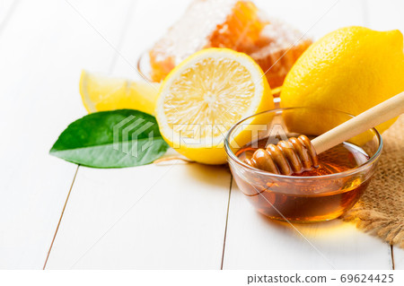 Honeycomb on dish with honey dipper with lemons on white wood background, Honeycomb on dish with honey dipper with lemons on white wood background, 69624425