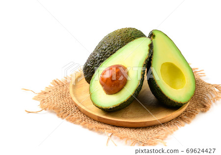 Avocado half on wood plate isolated on white background. Avocado half on wood plate isolated on white background. 69624427