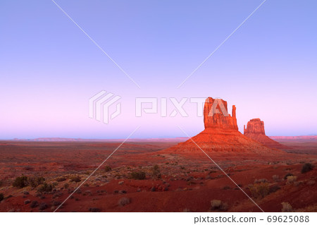 The last rays of the setting sun illuminate famous Buttes of Monument Valley 69625088