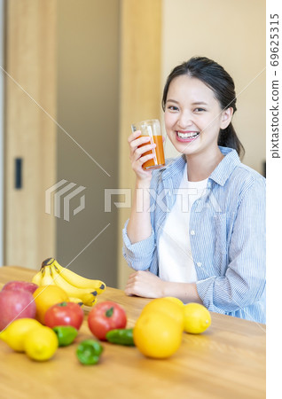 Image of a woman enjoying fruit (fruit juice) at home 69625315