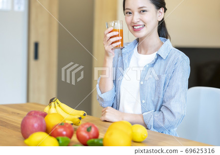 一個女人在家裡享受水果（果汁）的形象 69625316