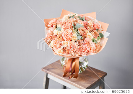Bouquet Peach and orange color. Beautiful bunch mixed flowers in wooden table. the work of the florist at a flower shop. Fresh cut flower. 69625635