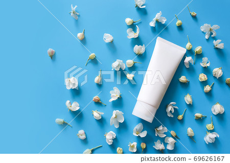 Top view of mock up of white squeeze bottle plastic tube for branding of medicine or cosmetics - cream, gel, skin care, toothpaste. Duds of blooming sakura on a blue background. Spa cosmetic product Top view of mock up of white squeeze bottle plastic tube for branding of medicine or cosmetics - cream, gel, skin care, toothpaste. Duds of blooming sakura on a blue background. Spa cosmetic product 69626167