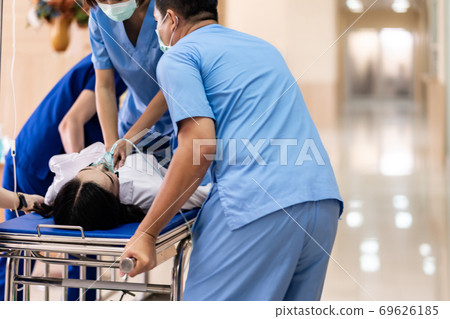 Medical team do CPR to injured patient on gurney 69626185