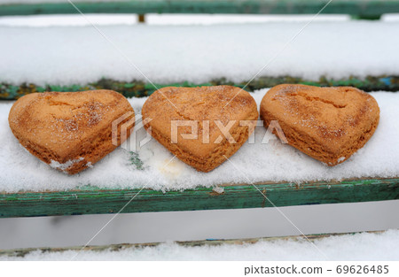 Homemade cookies with sugar and cinnamon in the form of hearts on a background of snow 69626485