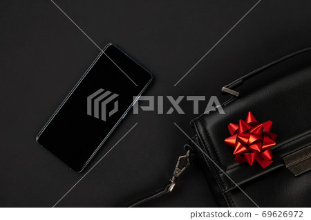 Creative flat lay top view composition with bag, smartphone and bow Creative flat lay top view composition with bag, smartphone and bow 69626972