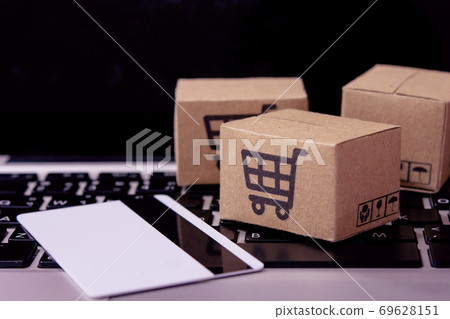 Shopping online. Credit card and cardboard box with a shopping cart logo on laptop keyboard. Shopping service on The online web. offers home delivery. Shopping online. Credit card and cardboard box with a shopping cart logo on laptop keyboard. Shopping service on The online web. offers home delivery. 69628151